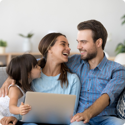 family of three smiling whilst using laptop