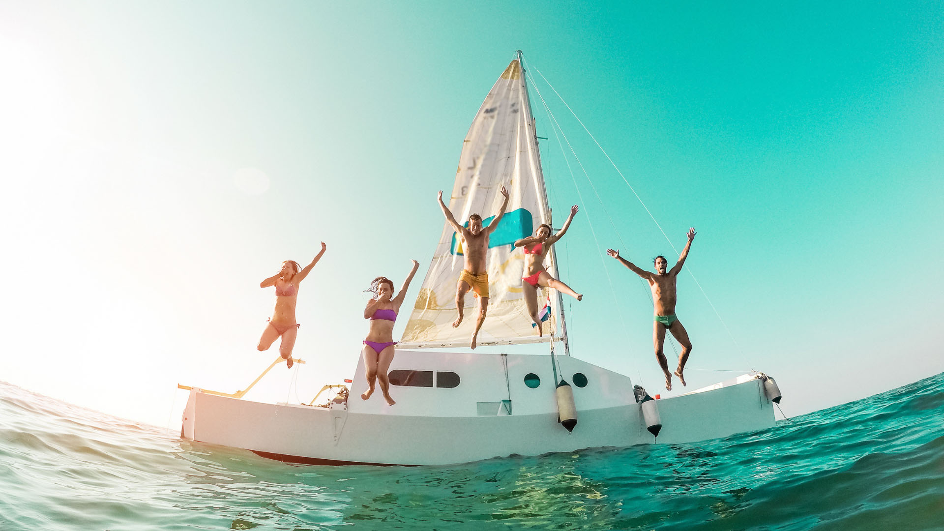 young people jumping off boat into ocean